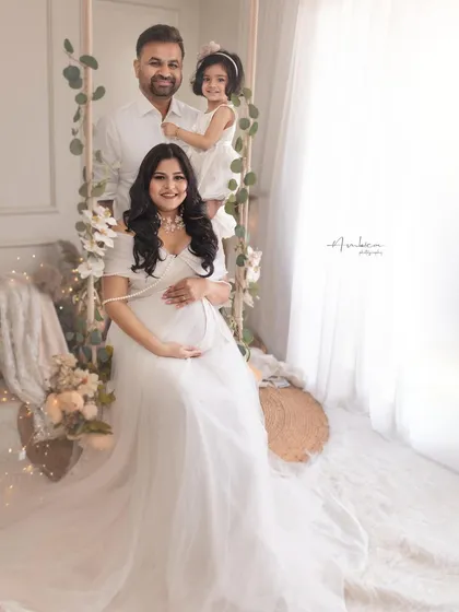 A beautiful family portrait on the studio swing, with their daughter joining in. The coordinated white outfits and happy smiles make this a perfect picture of a growing family.