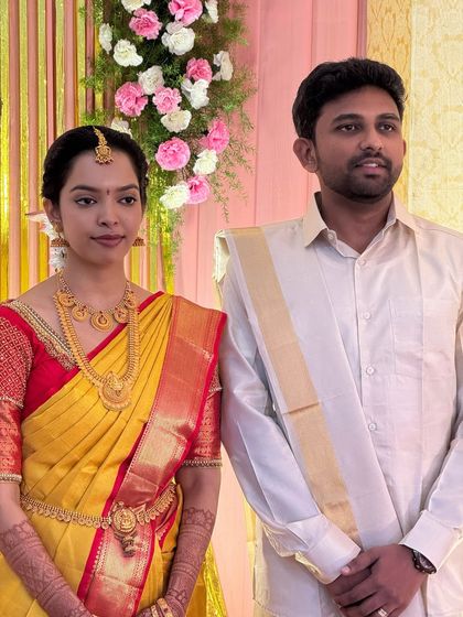 A candid moment of Dr. Sushmita and her groom during their Muhurtham. Her subtle makeup looks fresh and natural, perfect for the daytime ceremony, and complements her bright yellow and red saree.