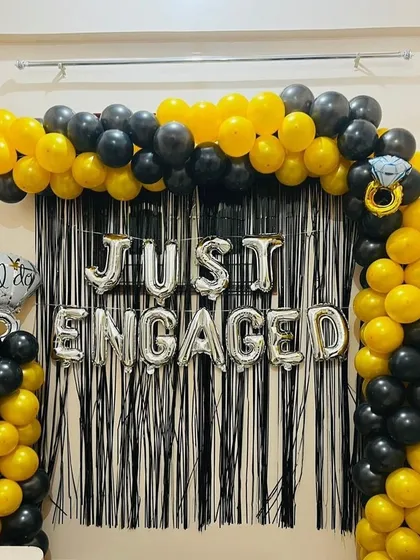 Announce your engagement in style. We created this bold and modern 'Just Engaged' photo backdrop using a black and yellow balloon arch against a black fringe curtain for a high-contrast, celebratory look.