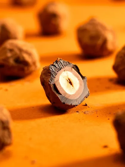 A cross-section of a hazelnut chocolate truffle, revealing the layers inside. This kind of detailed macro shot highlights the quality and complexity of the confection.