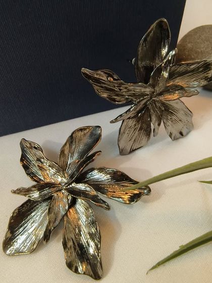A product shot of the adorable floral statement studs in a black metallic finish, a perfect mix of edgy and feminine.