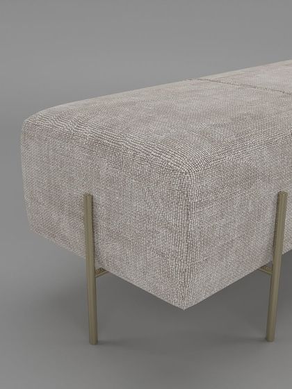 A close-up of the bench's corner, showing the fine-textured upholstery and the elegant design of the gold-finished metal legs.