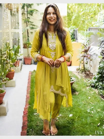 A full-length portrait of the bride in her beautiful yellow outfit, glowing with happiness during her Haldi ceremony.