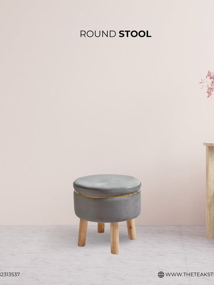 This simple and elegant round stool is upholstered in grey velvet with a gold accent trim. It's a versatile piece that can be used as extra seating, a footrest, or a small side table.