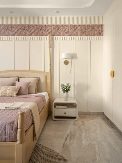 The four-poster bed with bamboo-style posts is dressed in dusty purple and beige linens, creating a serene and inviting atmosphere. The space feels both indulgent and intimate.