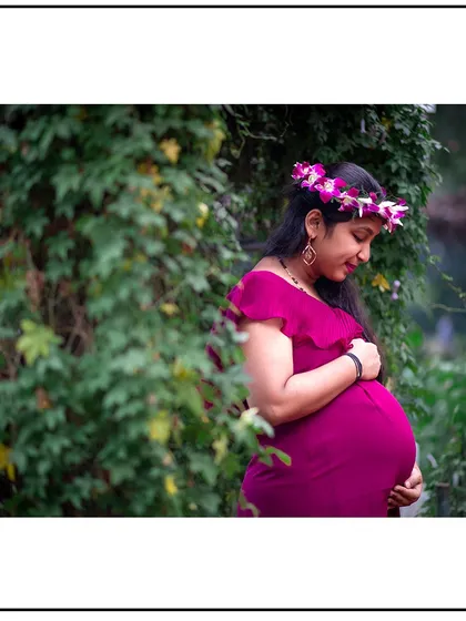 A quiet, contemplative solo portrait, with the mom-to-be looking down at her baby bump with love.