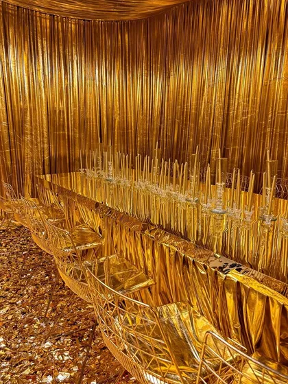A breathtaking dining setup where the entire room, from the walls and ceiling to the table and chairs, is draped in luxurious gold fabric.