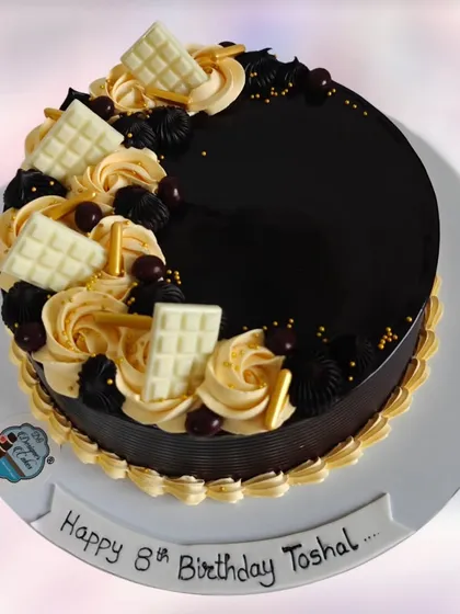A glossy chocolate drip cake decorated with white chocolate bars and caramel swirls. This is a truly indulgent cake for a special 8th birthday.