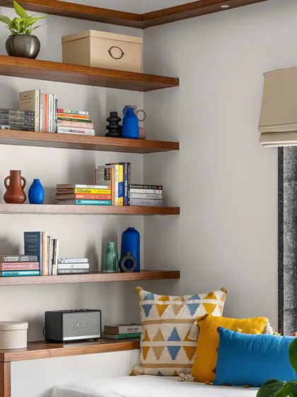 This cozy corner features floating wooden shelves perfect for a library, integrated with a comfortable window seat.