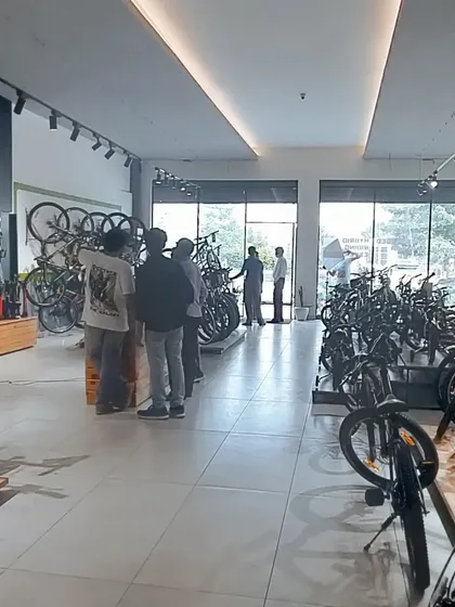 The interior of 'The Bicycle Studio', designed for an optimal customer experience. The layout is open and well-lit with track lighting, featuring clean display stands and organized product sections to make browsing easy and enjoyable.