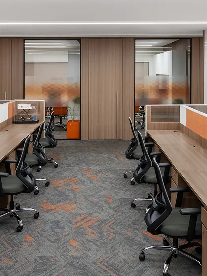 Workstations at the TajSATS office are arranged centrally with cabins along the perimeter, a layout proven effective in our previous projects. The design incorporates a consistent rust orange accent color and provides ample desk space for a comfortable work environment.