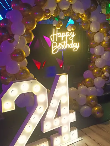 A 24th birthday celebration in a club. The gold and white balloon ring with a large light-up number '24' creates a perfect photo opportunity.