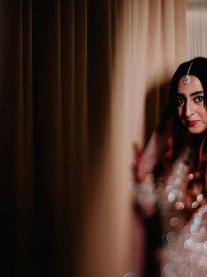 A candid portrait of a Muslim bride in a stunningly embellished gown, captured in a moment of quiet elegance.