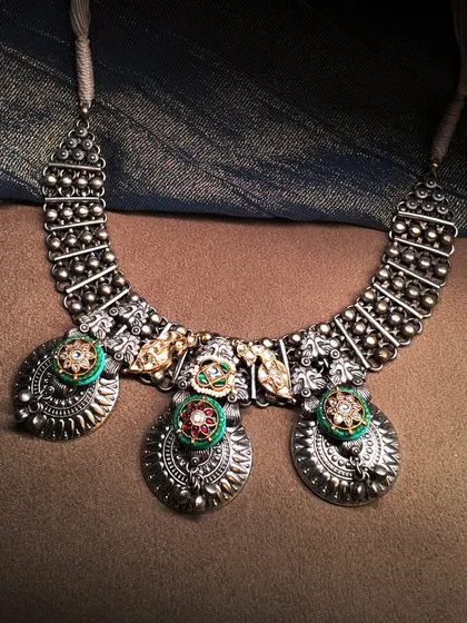 Mystic metals for a modern soul. This oxidized silver necklace features traditional coin-like motifs with colorful enamel work, blending heritage with a contemporary edge.