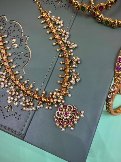 A beautiful Maharashtrian-style necklace with delicate pearl clusters and colored stones, paired with matching bangles. This set is perfect for a bride or for attending a wedding.
