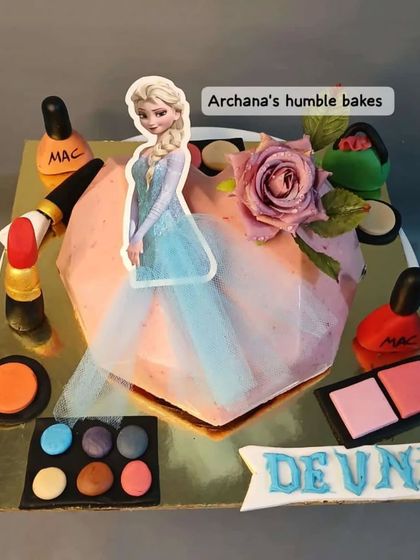 A unique combination of themes: a heart-shaped pinata cake with a Frozen theme, surrounded by edible makeup items.