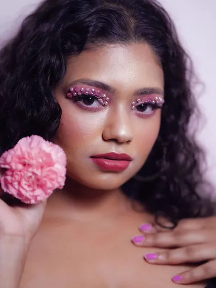 An artistic eye makeup look using pink eyeshadow and carefully placed pearl embellishments. This style adds texture and a high-fashion element, perfect for creative portraits and content creation.