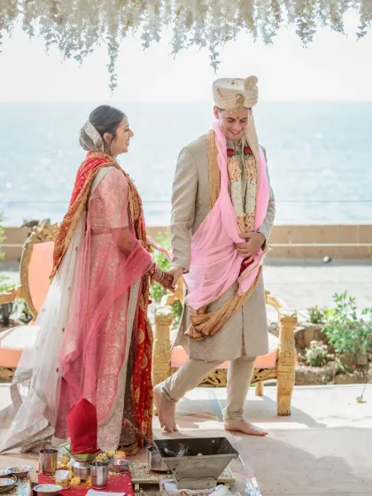 A candid moment from the wedding ceremony, showing the groom's happy expression as he participates in the rituals by the sea.