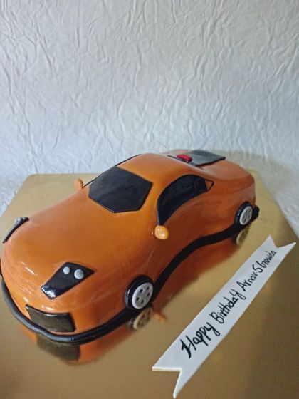 A 3D sculpted sports car cake in a vibrant orange color. This is a great example of how I can create realistic, edible models of your favorite things.