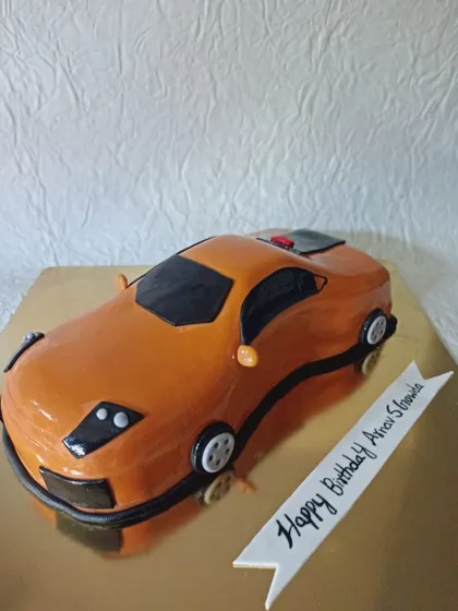 A sculpted cake in the shape of an orange sports car. This is a great example of how I can create hyper-realistic cakes based on your favorite things.