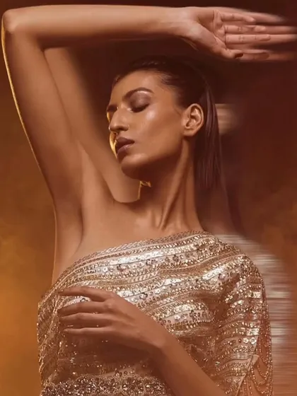 A beautifully lit, artistic shot for Kavita Arora's 'Noor' collection. The one-shoulder sequined top is captured in a soft, warm light, emphasizing the texture of the garment and the model's serene expression in a high-fashion context.
