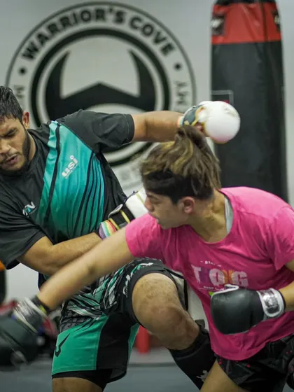 A female fighter trades punches with a male training partner, showing the high level of skill and mutual respect within our competition team.