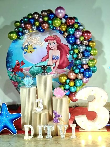 A detailed "The Little Mermaid" setup, featuring a seahorse prop, a large light-up number '3', and iridescent chrome balloons.