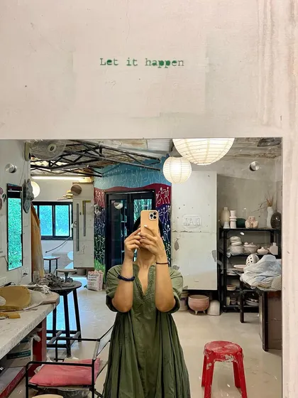 A mirror selfie in a pottery studio with the words "Let it happen." A reminder to embrace the creative process and allow things to unfold naturally.