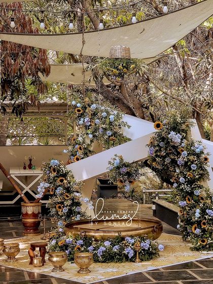 A vibrant Haldi ceremony setup with a stunning arrangement of sunflowers and blue florals. The traditional brass urlis and fabric drapes create a festive and joyful atmosphere.