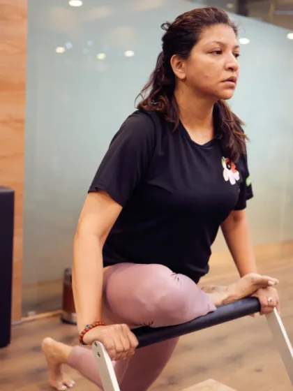 This client is performing a lunge using the Pilates chair, a versatile piece of equipment that is excellent for building leg strength and improving balance.