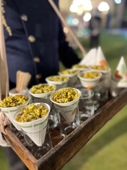 Jhal Muri, the beloved Bengali street food snack, served in convenient paper cones by our staff, perfect for guests to mingle and enjoy.