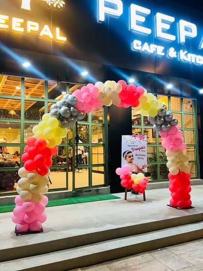 A classic and colorful balloon arch at the entrance of a cafe, welcoming guests to a birthday party.