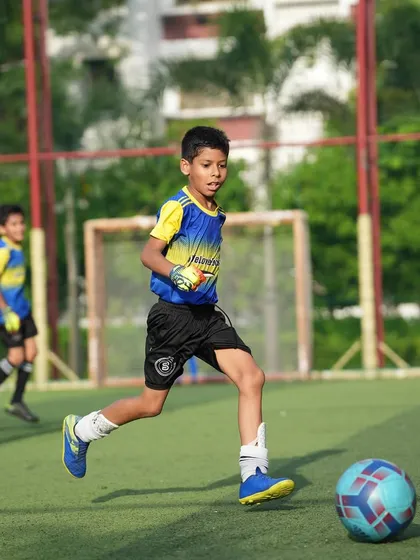We encourage players to experience all positions to foster a holistic football education. Here a player is seen dribbling past a defender.