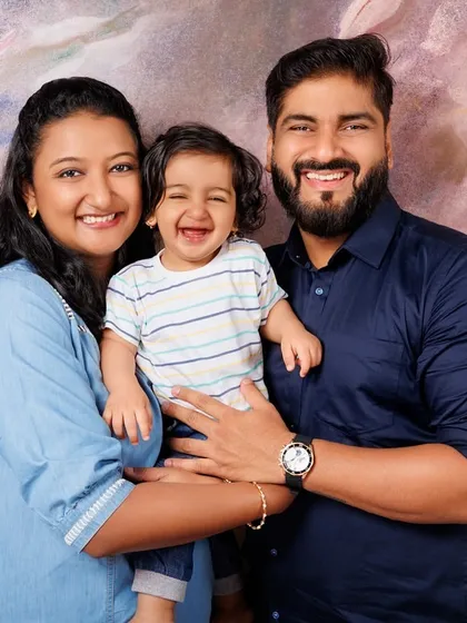 The happiest one year old! This family portrait captures the joy of celebrating a first birthday together. The floral backdrop adds a soft, celebratory feel to the studio photo.