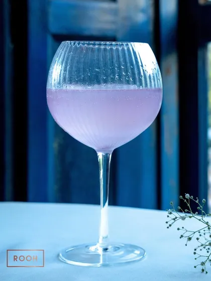 Our Lavender Magic cocktail, served in a beautiful ribbed glass. It's a light, floral, and refreshing choice for any celebration.