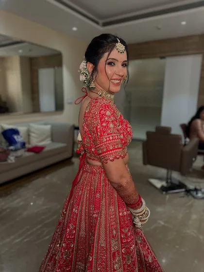 A smile that lights up the room. Her soft glam makeup and traditional red lehenga create a picture-perfect bridal moment.