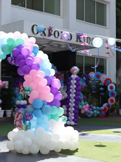 An enchanting 'Under the Sea' party with a 'My Little Pony' mermaid theme, featuring a rainbow balloon arch over clouds.