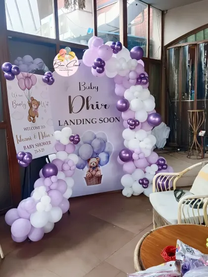 A 'Baby Dhir Landing Soon' teddy bear themed baby shower with a custom backdrop and a purple and white balloon garland.