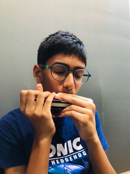 A young student practices his breathing and embouchure techniques on the harmonica. Mastering these fundamentals is key to producing a clear and expressive tone.