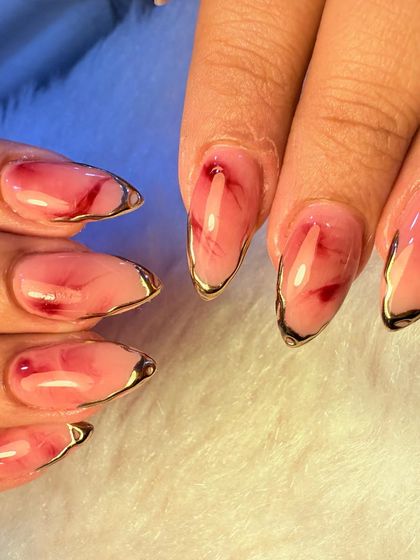 Another angle of the stunning red marble nails with a gold chrome edge. This view shows the glossy finish and the beautiful, subtle variations in the marble pattern.