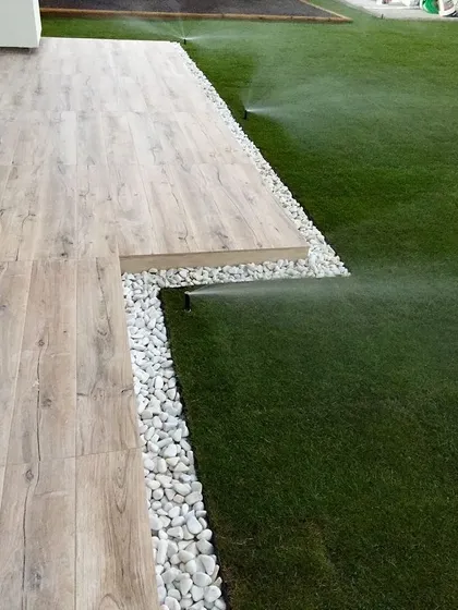 An automated sprinkler system in action on a new lawn. We install efficient irrigation systems to ensure your lawn stays green and healthy with minimal effort.