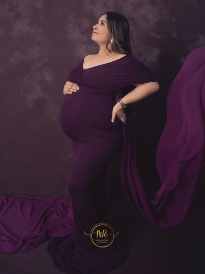 A classic side-profile maternity portrait in a deep purple gown. The flowing fabric adds a touch of drama, while the pose beautifully accentuates the baby bump.