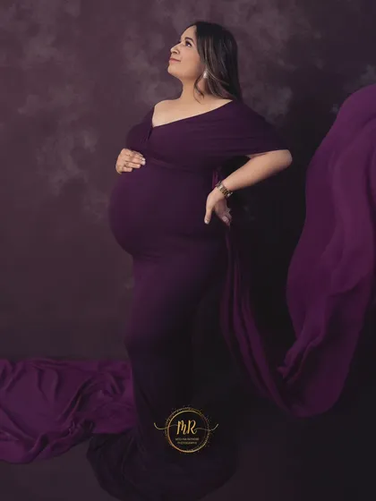 A classic side-profile maternity portrait in a deep purple gown. The flowing fabric adds a touch of drama, while the pose beautifully accentuates the baby bump.
