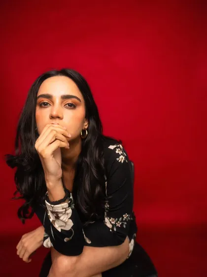 A closer crop on the red background, this shot is more intimate and focuses on the model's intense and captivating expression.