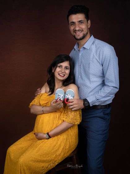 A happy couple showing off the first pair of baby shoes. It's a classic prop that symbolizes the new journey they are about to begin.