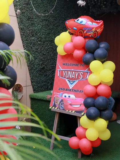 A personalized welcome sign for a "Cars" themed 2nd birthday, complete with a Lightning McQueen balloon, sets the tone for a speedy celebration.