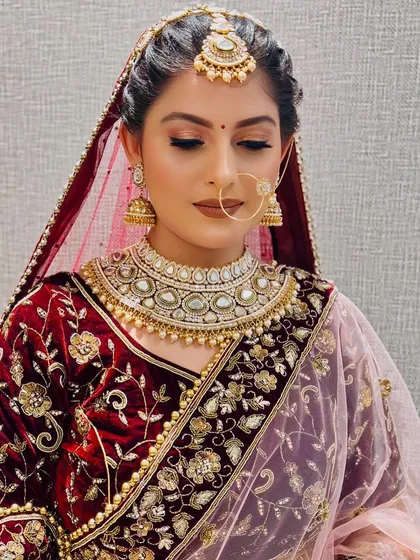 A three-quarter profile of the bride, showing how the makeup looks from different angles. The contouring on the cheekbones and the elegant hairstyle with the maang tikka are perfectly harmonized.