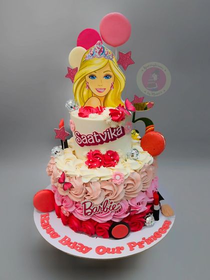 A beautiful two-tier Barbie cake with pink ombre rosettes and makeup-themed decorations.