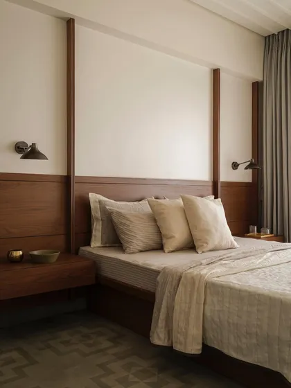 This bedroom in Apartment 1005 features a custom wood-paneled wall that integrates the headboard and floating nightstands. The design creates a warm, cohesive, and architectural element that grounds the room in natural materials.