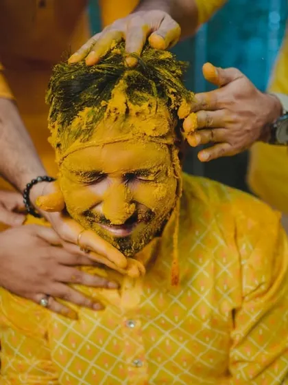 The groom gets his turn, being playfully covered in haldi by his friends and family.